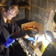 Rochelle hitting my sludgy-encrusted valve cover with some foaming cleaner and a wire brush on a drill.